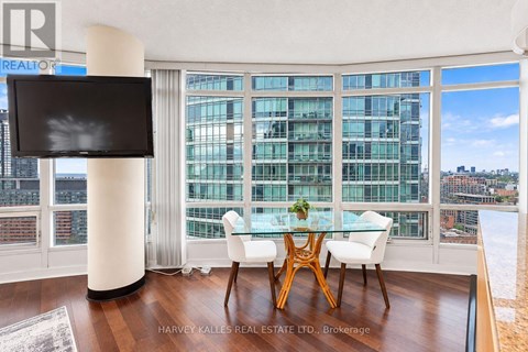 A modern dining room with a glass table and chairs, a flat screen TV, and a view of the city.