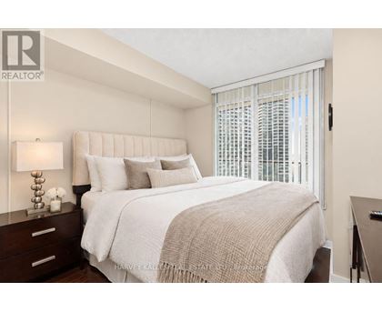 A bedroom with a large bed and a window with blinds.