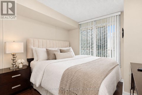 A bedroom with a large bed and a window with blinds.