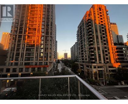 Two tall buildings with orange lighting and a street in between.
