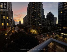 A cityscape at dusk with the sun setting behind the buildings.