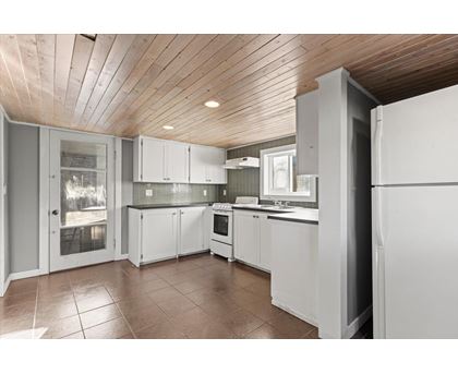 A kitchen with white cabinets and a wooden ceiling.