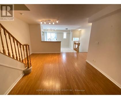 A spacious room with wooden floors and a staircase on the left side.