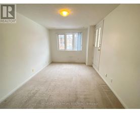 A room with a carpeted floor and a window with a view of a building outside.