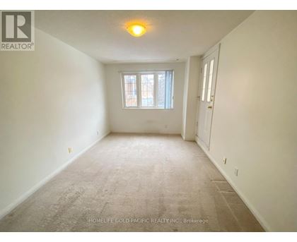 A room with a carpeted floor and a window with a view of a building outside.