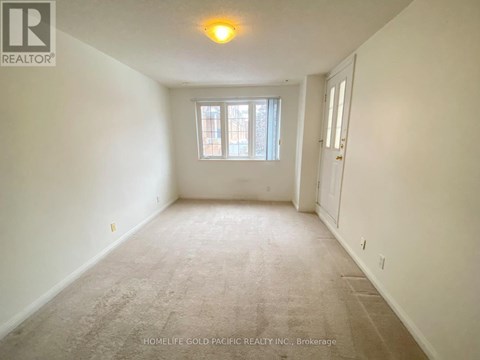A room with a carpeted floor and a window with a view of a building outside.