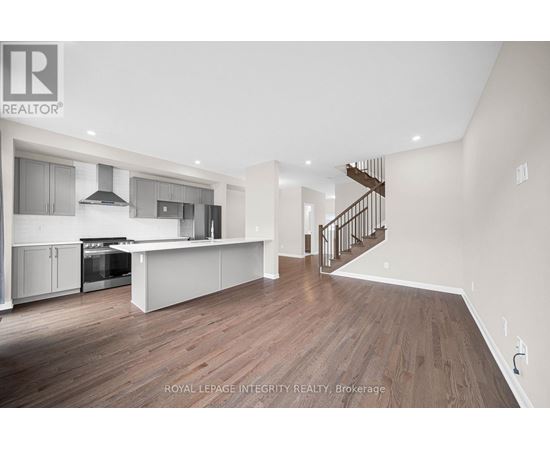A spacious kitchen with a stainless steel oven and a wooden floor.