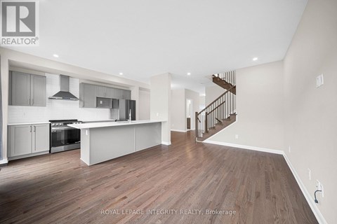 A spacious kitchen with a stainless steel oven and a wooden floor.