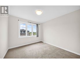 A room with a carpeted floor and a window showing a view of buildings outside.