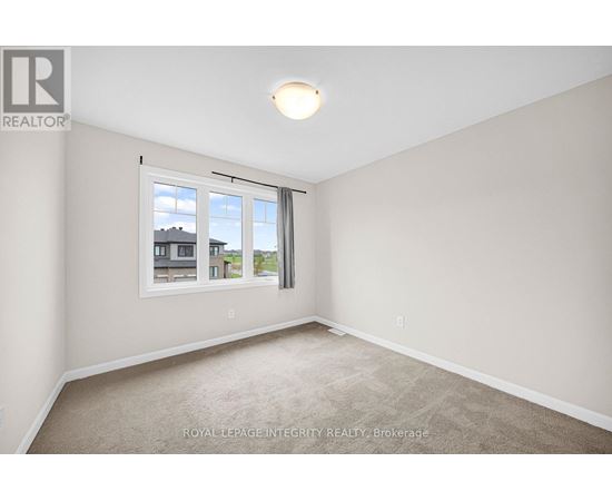 A room with a carpeted floor and a window showing a view of buildings outside.