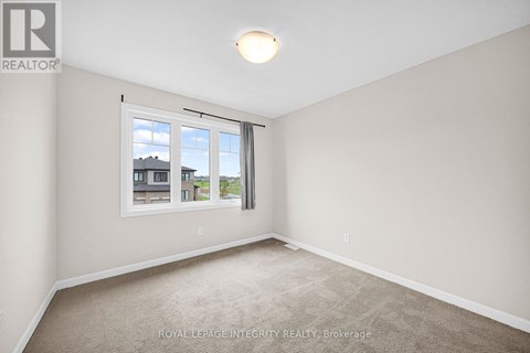 A room with a carpeted floor and a window showing a view of buildings outside.