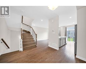A spacious room with wooden floors and a staircase with a wooden handrail.