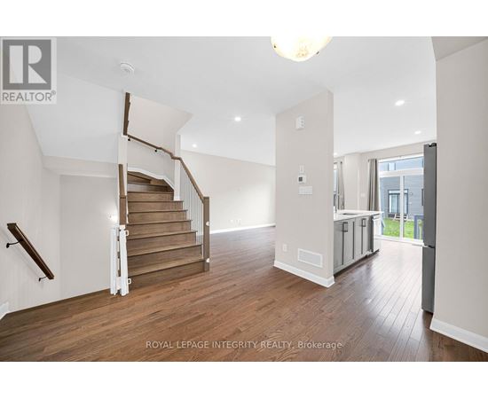 A spacious room with wooden floors and a staircase with a wooden handrail.