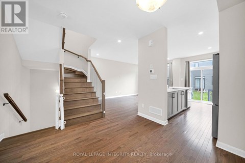 A spacious room with wooden floors and a staircase with a wooden handrail.