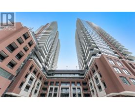 A tall building with a glass facade stands between two shorter buildings.