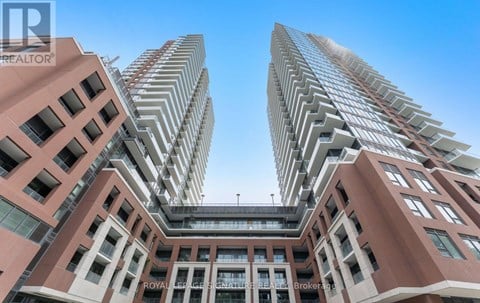 A tall building with a glass facade stands between two shorter buildings.