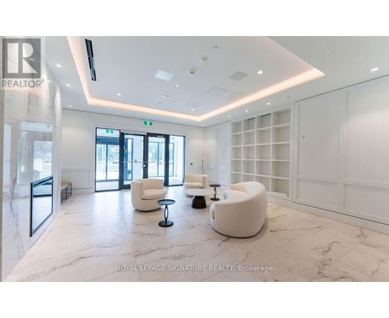A spacious waiting area with white furniture and marble flooring.