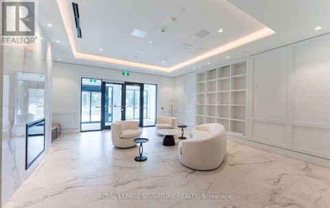 A spacious waiting area with white furniture and marble flooring.