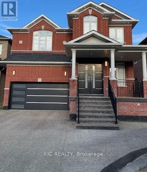 A red brick house with a black garage door and a black metal railing on the stairs.