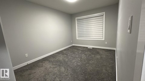 A room with a carpeted floor and a window with blinds.