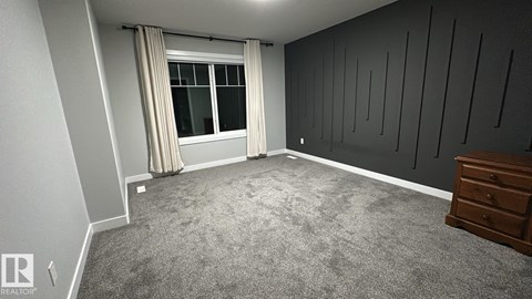 A bedroom with a carpeted floor and a window with curtains.
