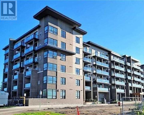 A large, multi-story residential building with balconies and a clear blue sky in the background.