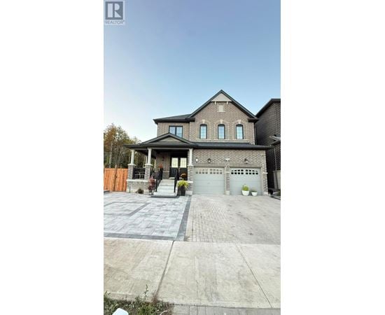 A house with a grey garage door and a brick driveway.