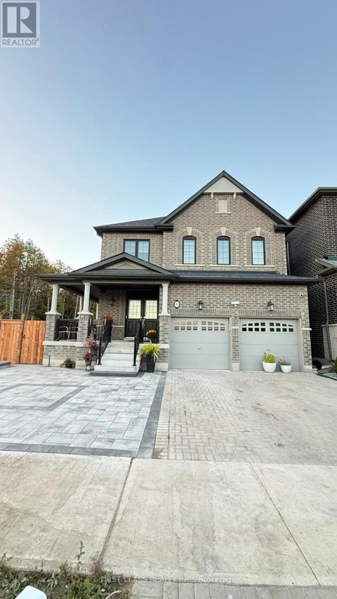 A house with a grey garage door and a brick driveway.