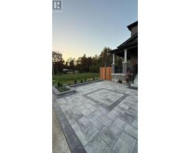 A stone patio leads to a house with a wooden gate.