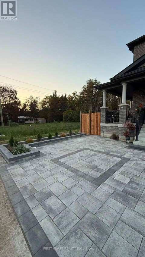 A stone patio leads to a house with a wooden gate.