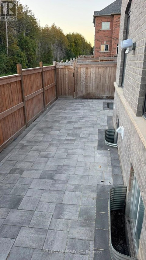A backyard with a wooden fence and a brick building in the background.