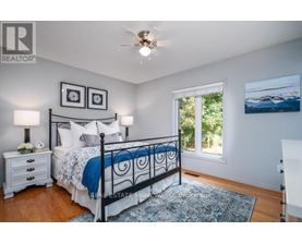 A bedroom with a bed, nightstands, and a ceiling fan.