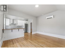A spacious room with wooden flooring and white walls.