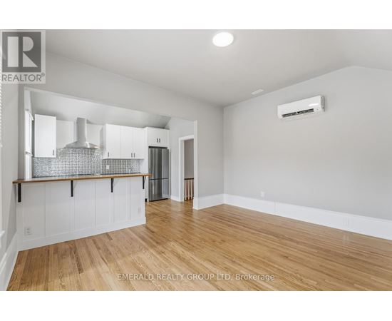 A spacious room with wooden flooring and white walls.