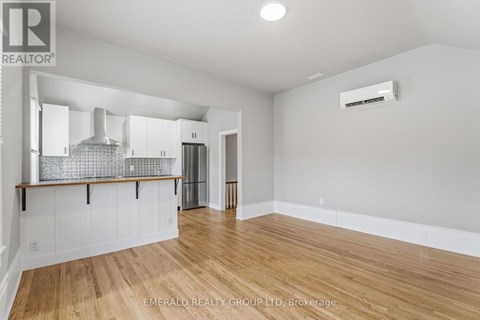 A spacious room with wooden flooring and white walls.