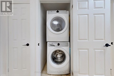 A white washing machine is in a small space between two doors.