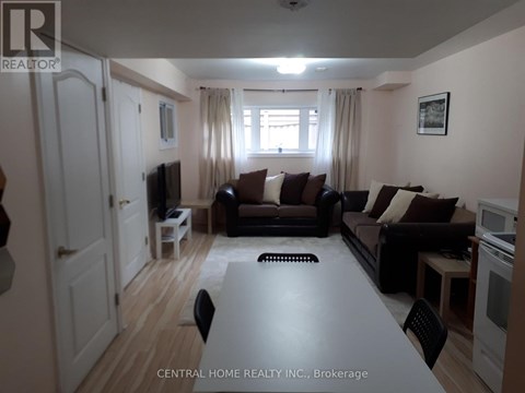 A living room with a couch, chairs, and a television.
