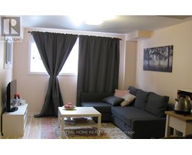 A living room with a grey couch, a coffee table, and a television.