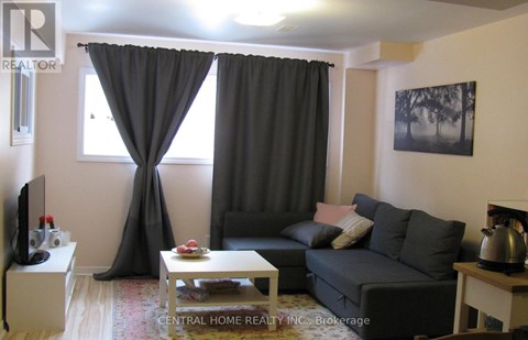 A living room with a grey couch, a coffee table, and a television.