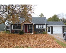 A house with a red door and a grey roof surrounded by fallen leaves.
