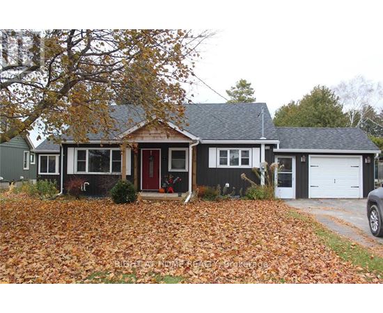 A house with a red door and a grey roof surrounded by fallen leaves.