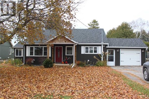 A house with a red door and a grey roof surrounded by fallen leaves.