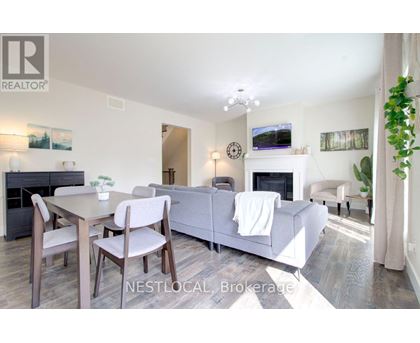 A living room with a grey couch, a wooden table and chairs, a fireplace, and a painting on the wall.