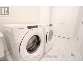 Two white Whirlpool washing machines in a laundry room.