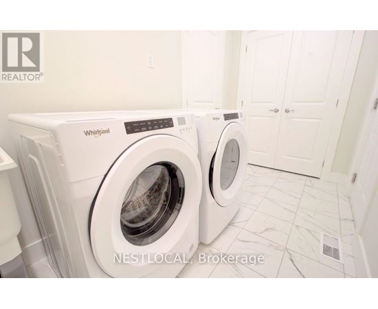 Two white Whirlpool washing machines in a laundry room.