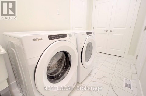 Two white Whirlpool washing machines in a laundry room.
