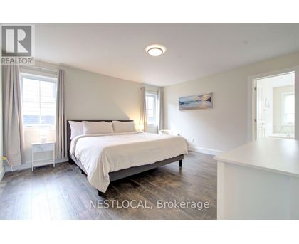 A bedroom with a large bed and a window with curtains.