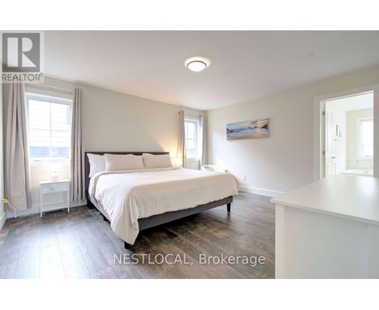 A bedroom with a large bed and a window with curtains.