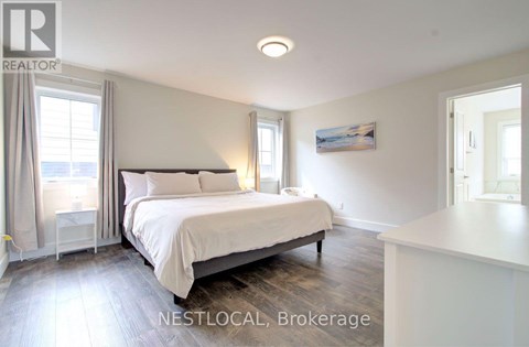 A bedroom with a large bed and a window with curtains.