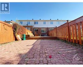 A brick pathway leads to a wooden fence and a building.
